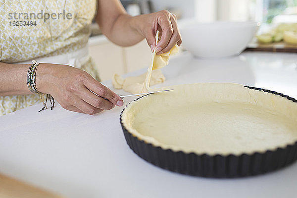 Nahaufnahme einer Frau  die die Kante der Kuchenkruste schneidet