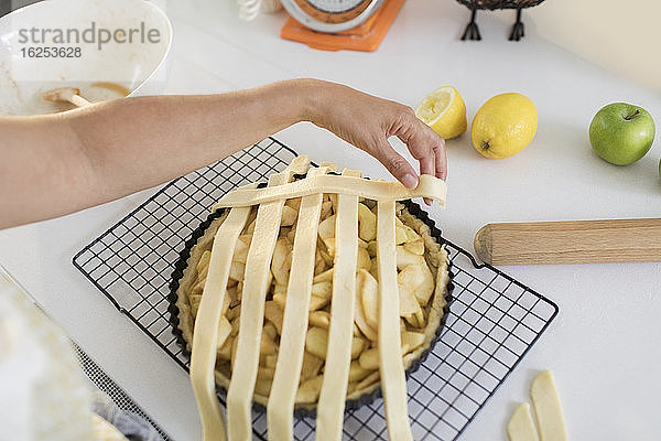 Frau arrangiert Gitter über Apfelkuchen in der Küche