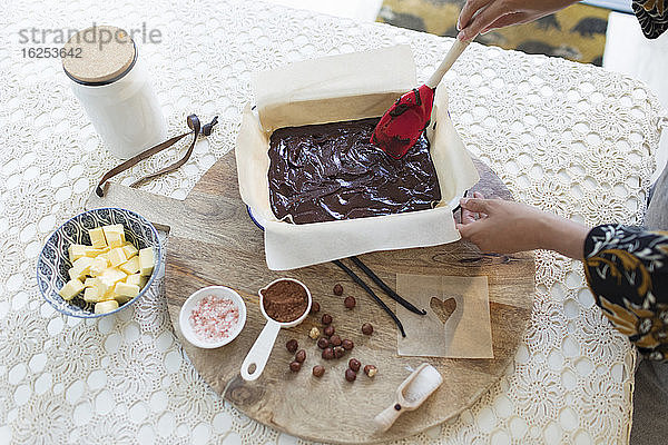 Frau backt Schokoladenkuchen am Esstisch