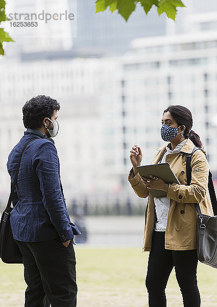 Geschäftsleute mit Gesichtsmasken reden im Stadtpark