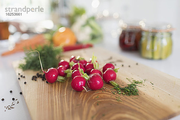 Rote Radieschen und Kräuter auf dem Schneidebrett aus nächster Nähe