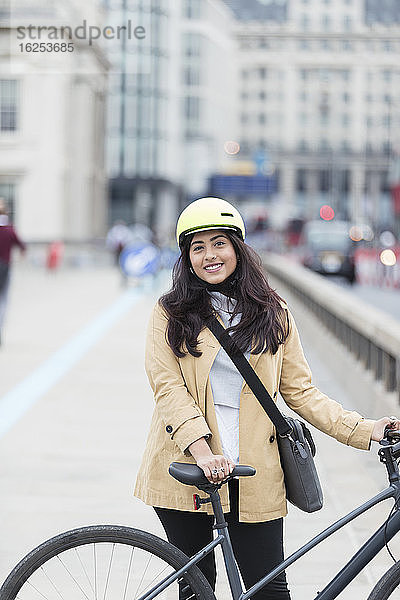 Porträt einer lächelnden Geschäftsfrau mit Fahrrad auf der Stadtbrücke