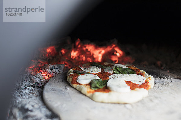 Nahaufnahme von hausgemachter Pizza auf der Schale im Pizzaofen