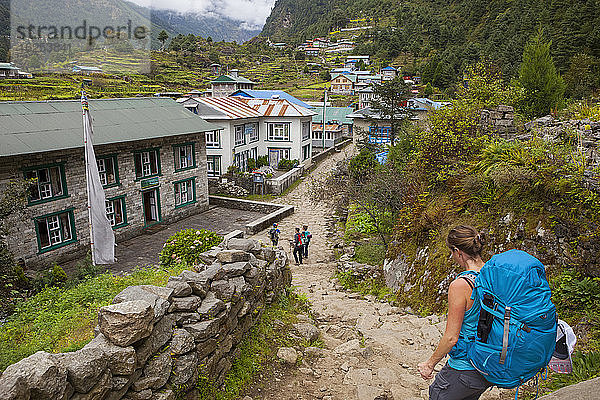 Eine Gruppe auf Rucksacktour durch eine Stadt in einem Tal des Himalaya; Nepal