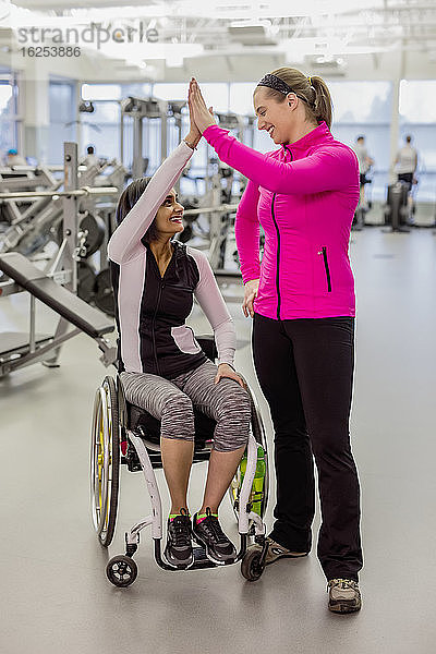 Eine querschnittsgelähmte Frau und ihr Trainer geben nach einem erfolgreichen Training in einer Freizeiteinrichtung ein High Five: Sherwood Park  Alberta  Kanada