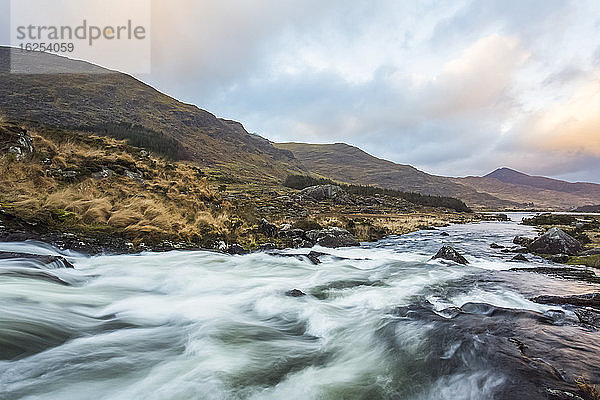 Kaskaden an einem Fluss im Black Valley in Kerry mit den MacGillycuddy's Reeks im Hintergrund an einem bewölkten Tag; Grafschaft Kerry  Irland