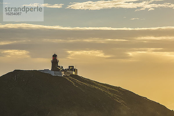 Die Silhouette des Leuchtturms Ballycotton wird von der Morgensonne beschienen; Ballycotton  Grafschaft Cork  Irland