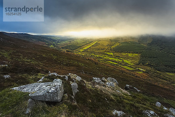 Felsvorsprünge in den Silvermine Mountains  die Sonne geht hinter einigen tiefhängenden Wolken auf; Grafschaft Tipperary  Irland