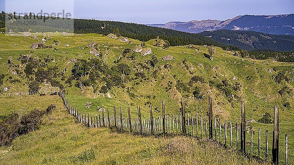 Ein Zaun verläuft entlang des hügeligen und zerklüfteten Ackerlandes von Neuseeland; Nordinsel  Neuseeland