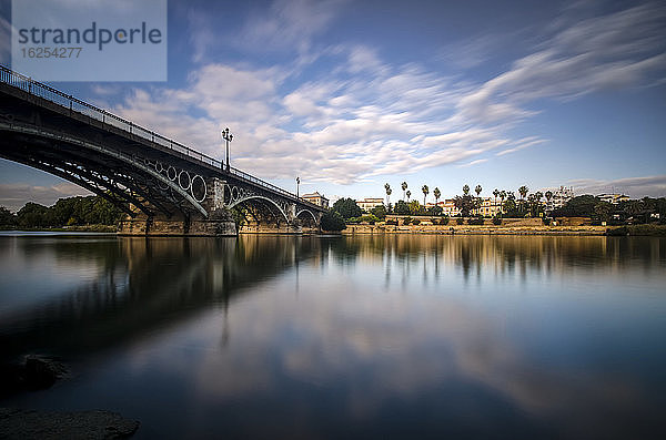 Spiegelung eines Flusses und der Guadalquivir-Brücke in der Abenddämmerung; Sevilla  Andalusien  Spanien