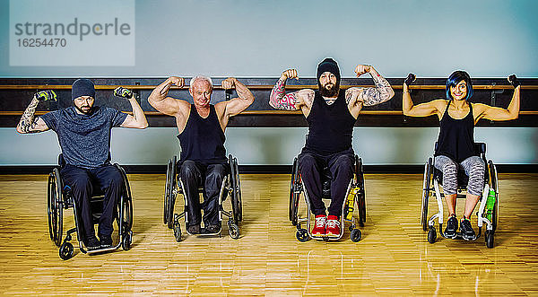 Eine Gruppe querschnittsgelähmter Freunde  die herumalbern und ihre Muskeln nach einem Training in einer Fitnesseinrichtung zeigen: Sherwood Park  Alberta  Kanada