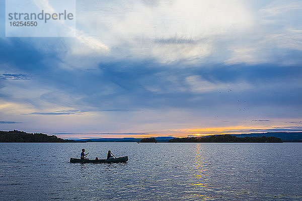 Mann und Frau paddeln bei Sonnenuntergang auf dem See Lough Derg mit einem Kanu; Grafschaft Clare  Irland