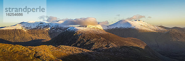 Panoramablick auf die morgendlichen Sonnenstrahlen  die im Winter auf die schneebedeckten MacGillycuddy's Reeks treffen  gesticktes Panorama; Grafschaft Kerry  Irland