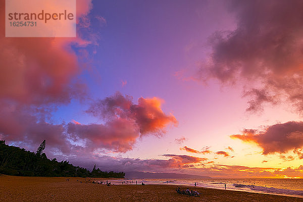 Silhouette von Surfern  die am Kelki Beach am Wasser stehen  mit dramatisch leuchtenden Wolken darüber bei Sonnenuntergang; Oahu  Hawaii  Vereinigte Staaten von Amerika