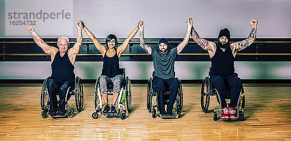 Eine Gruppe querschnittsgelähmter Freunde hebt nach einem Training in einer Fitnesseinrichtung gemeinsam die Hand zum Sieg: Sherwood Park  Alberta  Kanada