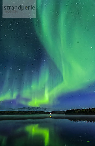 Leuchtend grünes Polarlicht tanzt wie Feuer über dem Birch Lake mit Reflexionen  Inneres Alaska im Herbst; Fairbanks  Alaska  Vereinigte Staaten von Amerika