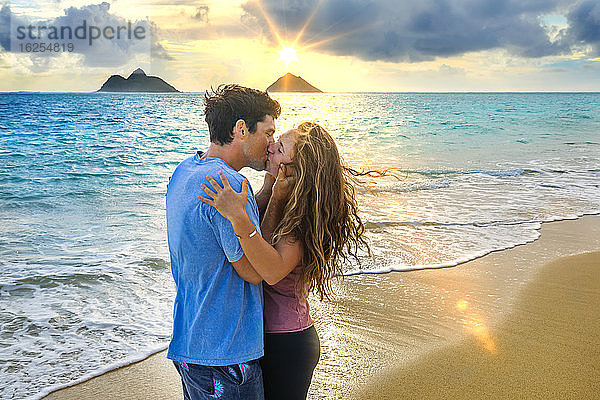 Ein Paar steht bei Sonnenuntergang küssend am Strand von Lanakai auf der hawaiianischen Insel Oahu; Lanakai  Oahu  Hawaii  Vereinigte Staaten von Amerika