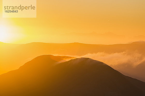 Silhouette eines Hügels in Kerry bei Sonnenaufgang mit Schneeverwehungen von der Spitze  MacGillycuddy's Reeks; Grafschaft Kerry  Irland