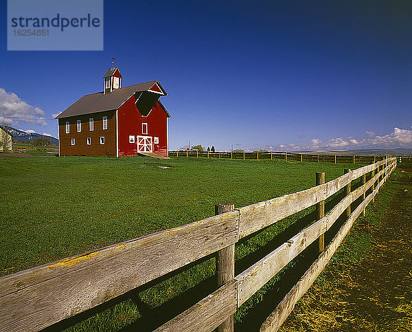 Landwirtschaft - Gut erhaltene rote Ranch-Scheune mit einer Kuppel  um 1890  umgeben von einem Holzzaun / Joseph  Oregon  USA.