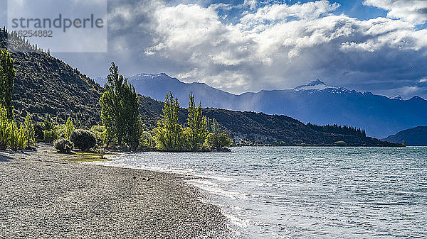 Ein Fluss fließt durch die bergige Landschaft von Albert Town auf der Südinsel Neuseelands  wobei Regen aus Sturmwolken fällt; Albert Town  Region Otago  Südinsel  Neuseeland