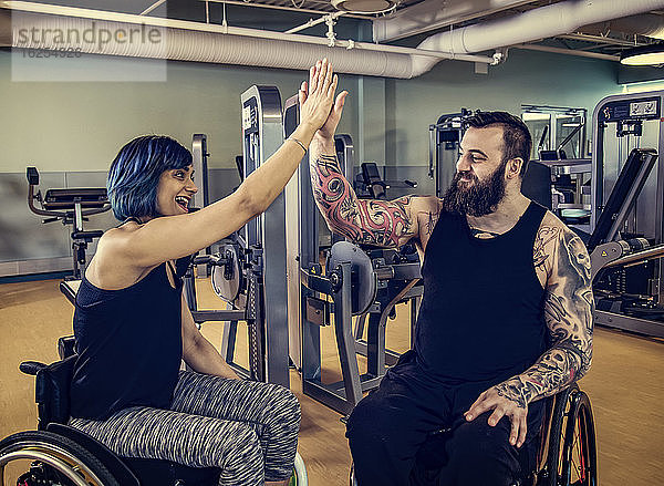 Zwei querschnittsgelähmte Freunde  die sich nach dem Training in einer Fitnesseinrichtung gegenseitig ein High Five geben: Sherwood Park  Alberta  Kanada