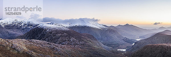 Panoramablick auf die MacGillycuddy's Reeks im Schnee und das Black Valley in der Morgendämmerung im Winter  zusammengenähtes Komposit; Grafschaft Kerry  Irland