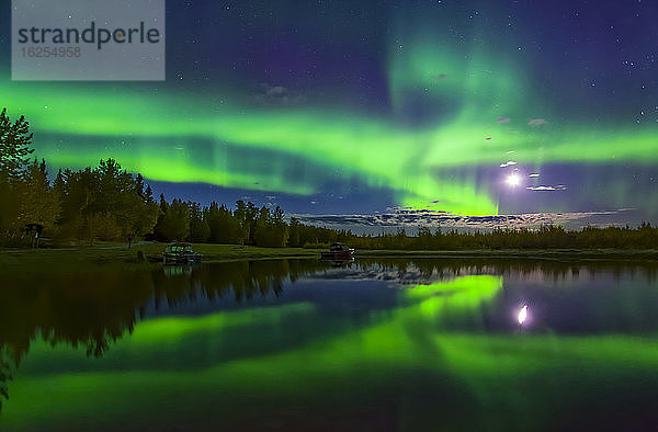 Leuchtend grünes Polarlicht  das mit dem Mond über dem Harding-See mit Spiegelungen weht  Inneres Alaska im Herbst; Fairbanks  Alaska  Vereinigte Staaten von Amerika