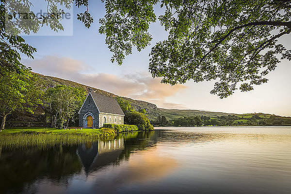 Alte Kapelle von Gougane Barra  an einem See gelegen und bei Sonnenaufgang von grünen Bäumen umrahmt; Gougane Barra  Grafschaft Cork  Irland