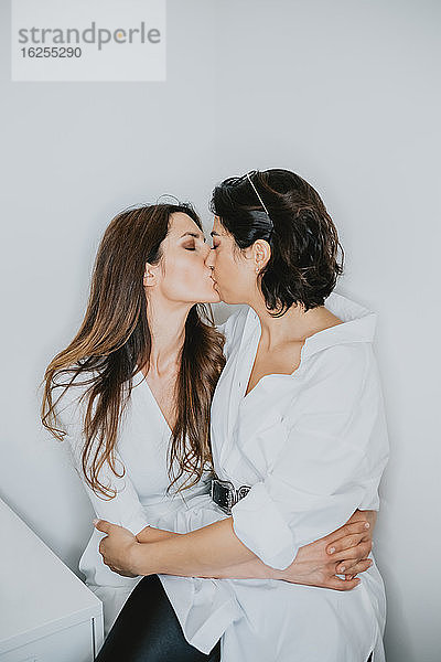Porträt von zwei Frauen mit braunem Haar  die sich umarmen und küssen.