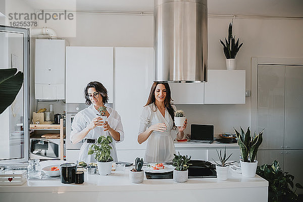 Zwei lächelnde Frauen mit braunem Haar stehen in einer Küche und bereiten Essen zu.