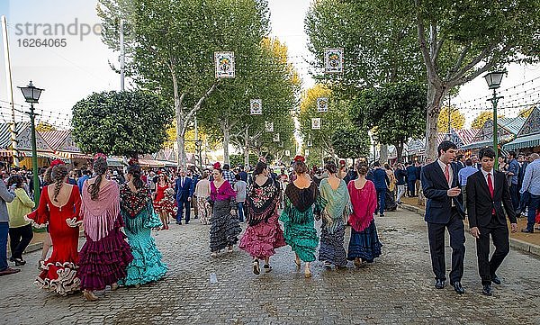 Feiernde Spanier in traditioneller Kleidung vor Festzelten  Frauen in bunten Flamencokleidern  Casetas  geschmückte Straße  Feria de Abril  Sevilla  Andalusien  Spanien  Europa