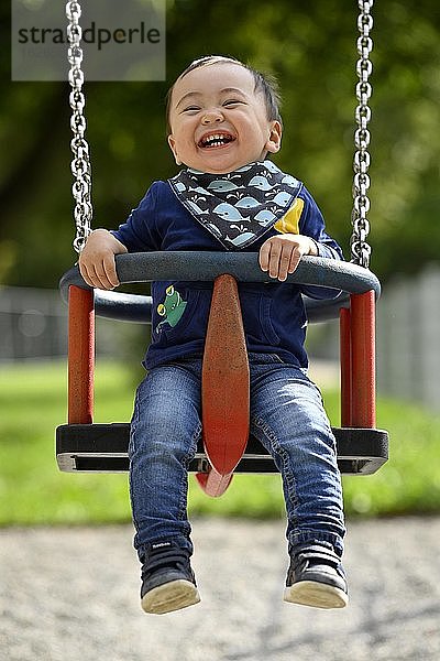 Kleinkind  Junge  14 Monate  multiethnisch  auf Kinderschaukel  lacht  Blaubeuren  Baden-Württemberg  Deutschland  Europa