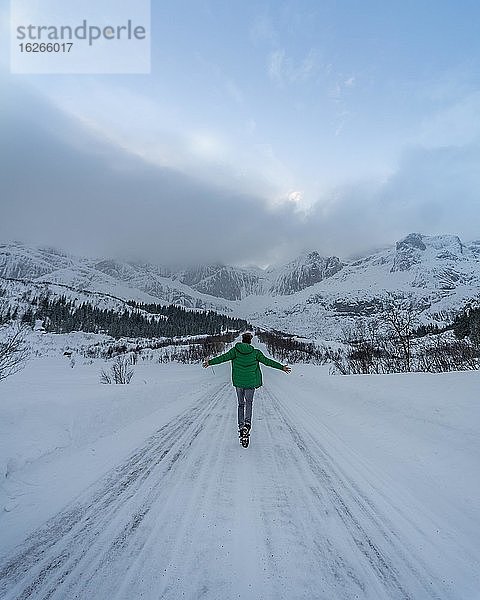Person läuft auf verschneiter Straße  bei Nusfjord  Lofoten  Nordland  Norwegen  Europa