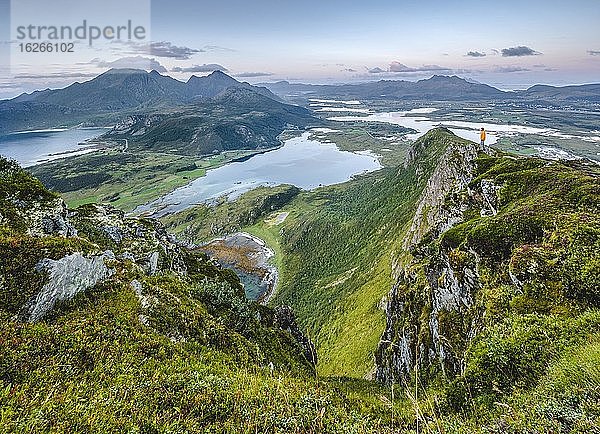 Winzige Person steht am Gipfel und blickt auf die Weite der Lofotenberge  Offersoykammen  Vestvågøy  Lofoten  Nordland  Norwegen  Europa