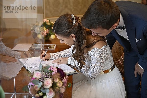 Brautpaar unterschreibt Eheurkunde im Standesamt  Glasfassade wegen Corona-Krise  Karlsruhe  Baden-Württemberg  Deutschland  Europa