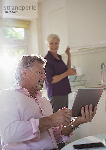 Älteres Ehepaar mit digitalem Tablet-Gespräch in der Küche