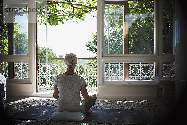 Heitere Frau meditiert an ruhigem  sonnigem Balkonfenster
