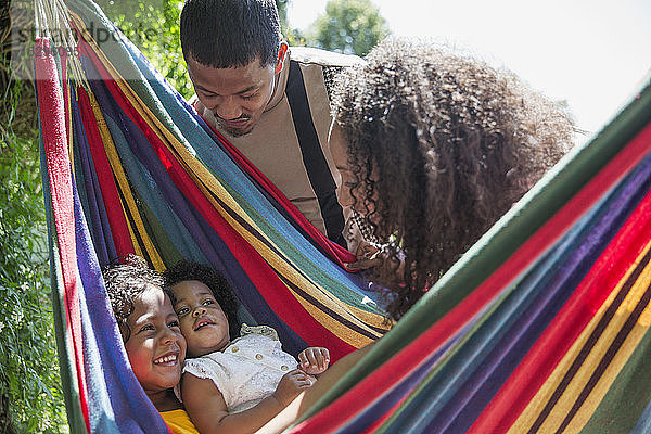 Eltern beobachten glückliche Töchter in sonniger Sommerhängematte