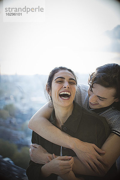 Glückliches junges Paar lacht und umarmt sich auf dem Balkon