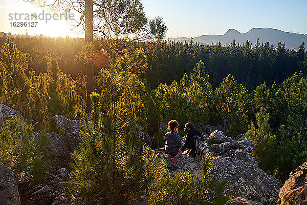 Junges Wanderpaar entspannt sich auf Felsen in sonnigen Wäldern