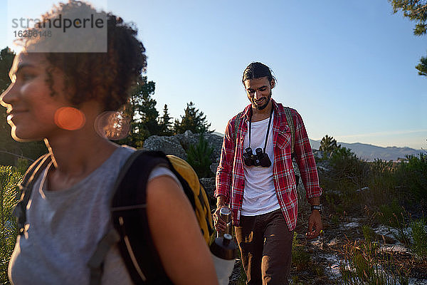 Junges Paar mit Fernglas beim Wandern in sonniger Natur