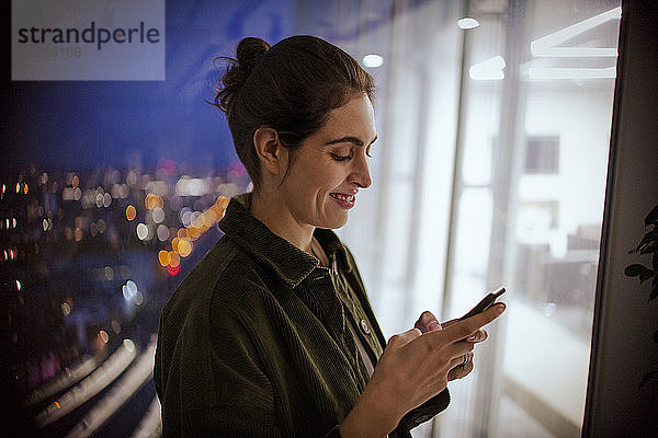 Geschäftsfrau benutzt nachts im Büro ein Smartphone