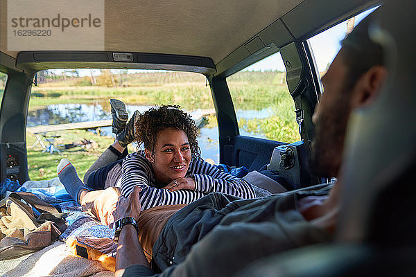 Glückliches junges Paar entspannt sich und zeltet auf dem Rücksitz eines Autos