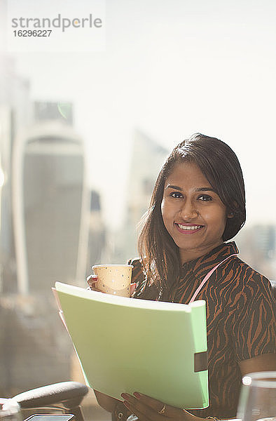 Porträt einer glücklichen Geschäftsfrau mit Papierkram am sonnigen Bürofenster