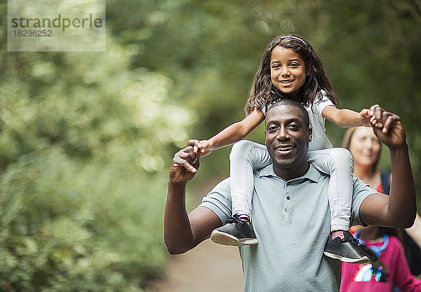 Vater trägt Tochter auf den Schultern auf Waldweg