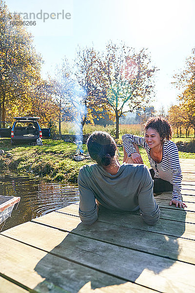 Glückliches junges Paar entspannt sich am sonnigen Herbstanleger in der Nähe des Campingplatzes