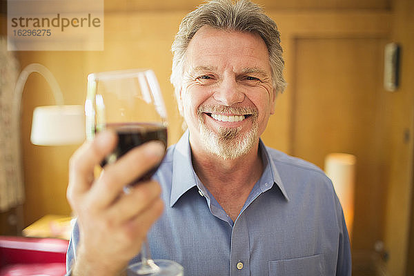 Porträt eines glücklichen  sorglosen älteren Mannes  der Rotwein trinkt