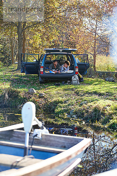 Junges Paar entspannt im Auto am sonnigen Herbstufer des Sees