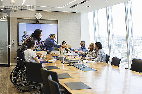 Geschäftsleute bringen Mitarbeitern im Konferenzraum das Mittagessen