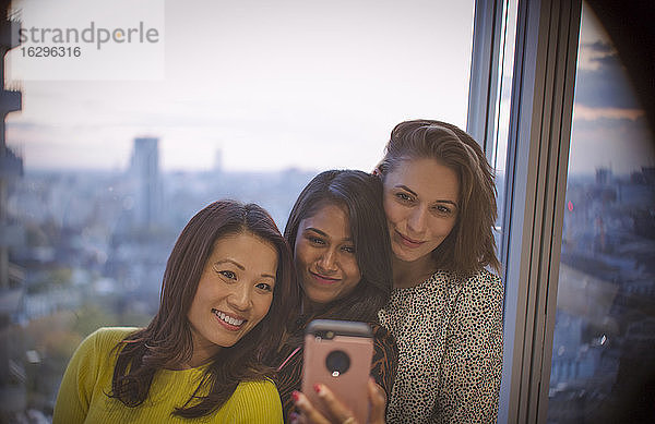 Geschäftsfrauen beim Selfie mit Smartphone am Fenster des Hochhauses